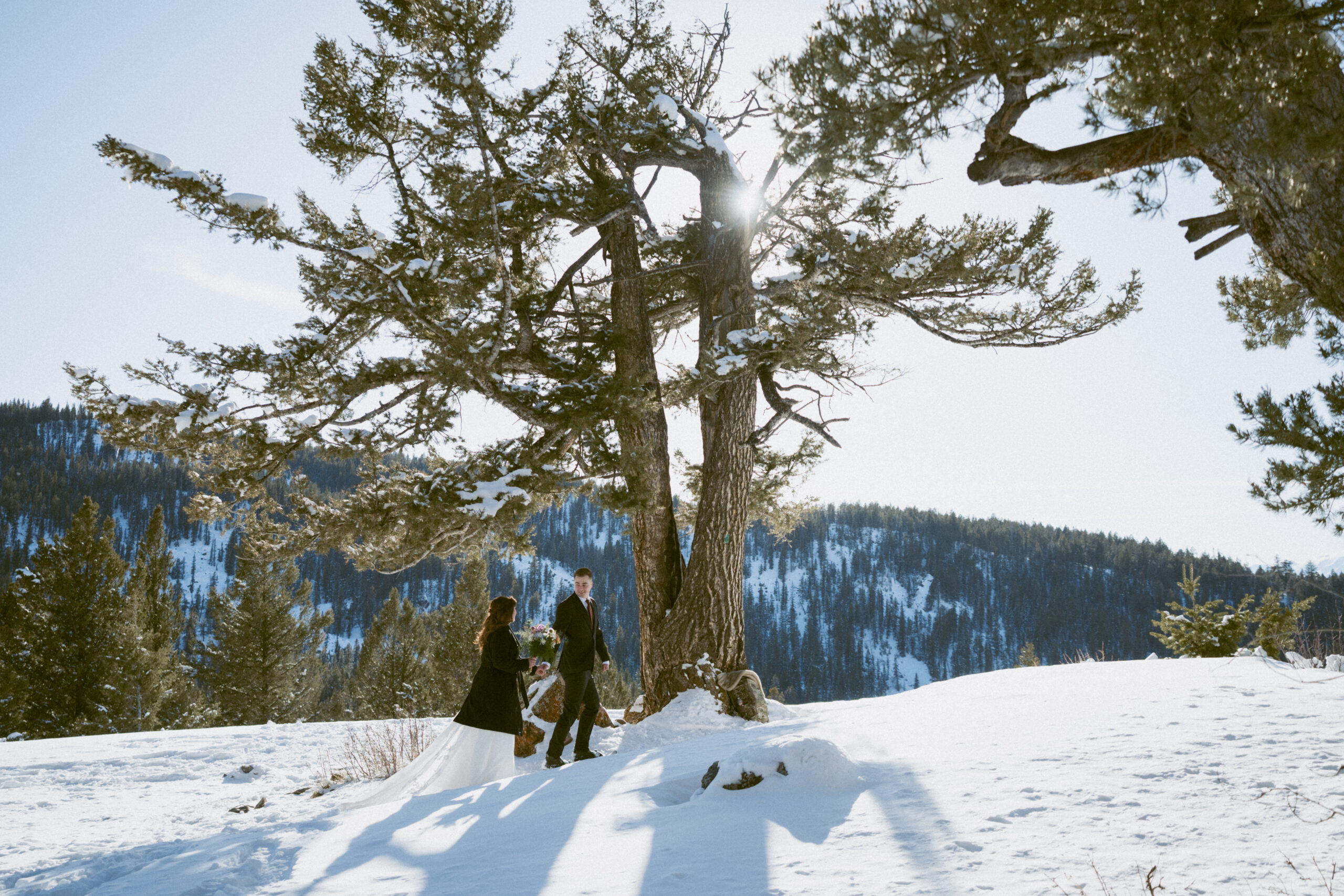 Wedding couple snowshoeing to The Wedding Tree in Wyoming. 