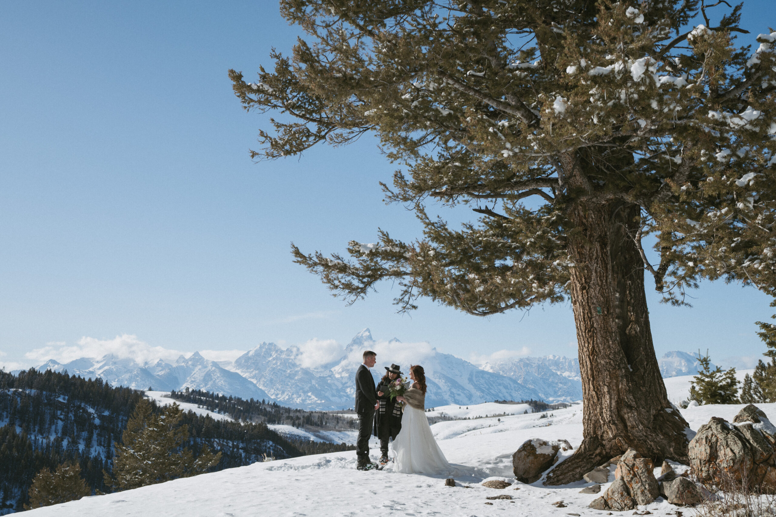 Couple standing at The Wedding Tree in Wyoming with the majestic Grand Tetons on the horizon. 