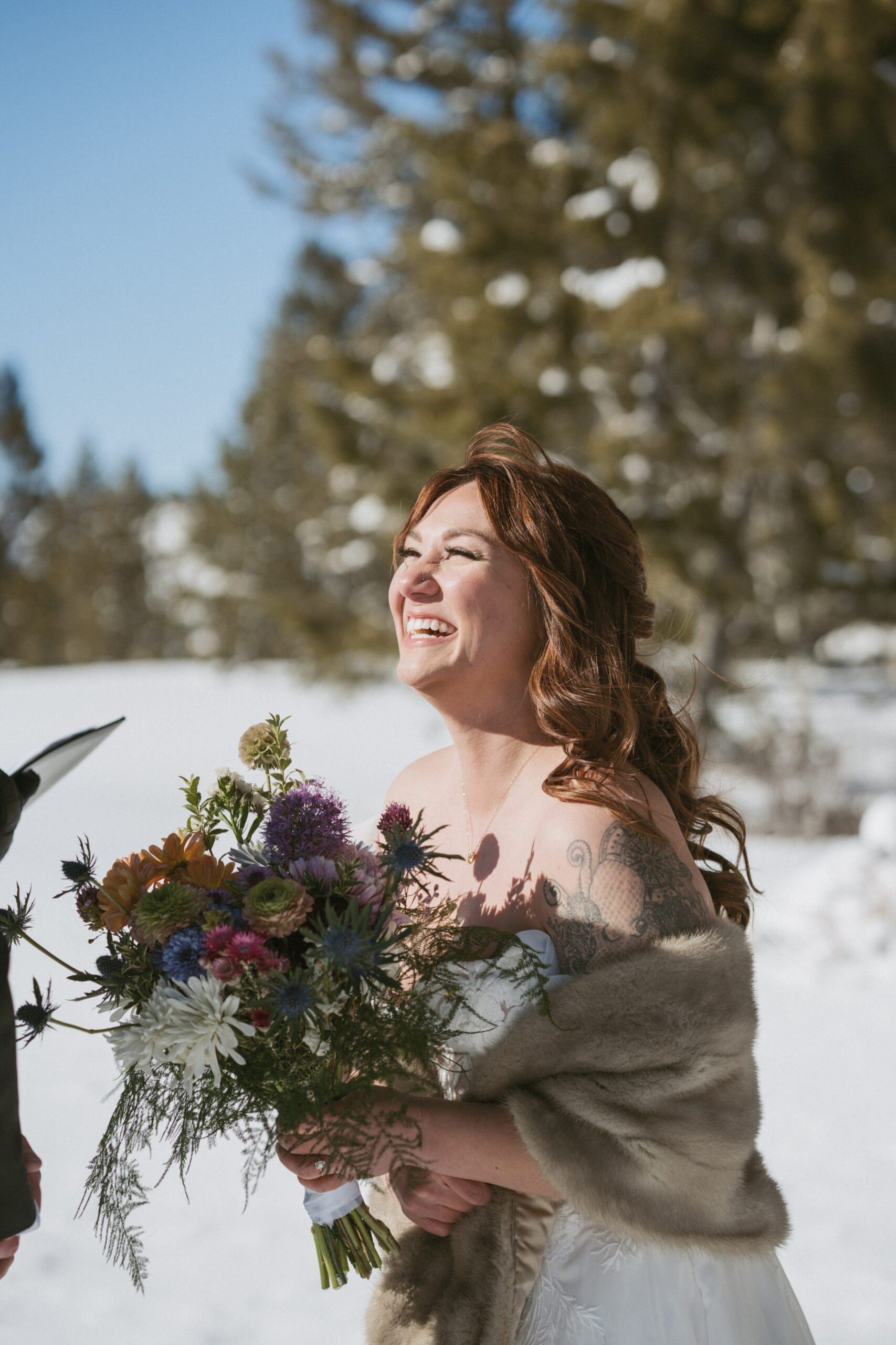 Bride happily laughing while holding here bouquet during her wedding ceremony in the Grand Teton National Park. 